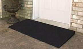 Black doormat at brick house entrance.