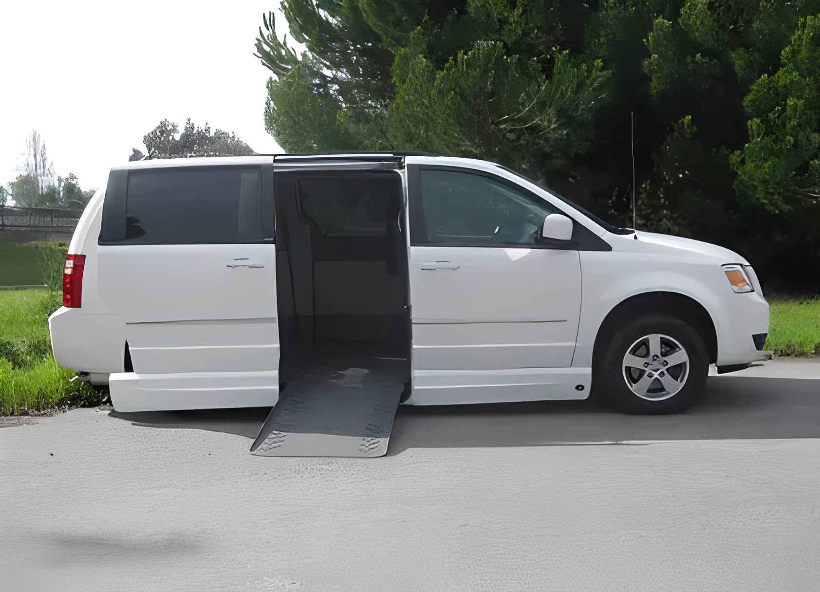 White wheelchair-accessible van with ramp extended on side.