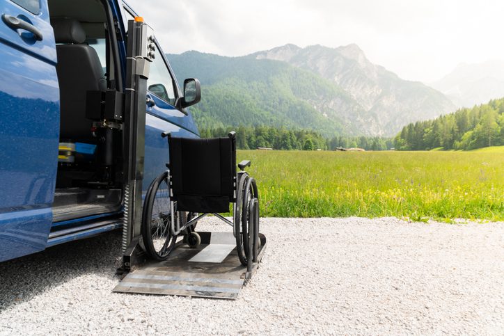 Empty wheelchair positioned on a ramp leading outdoors to a scenic landscape.