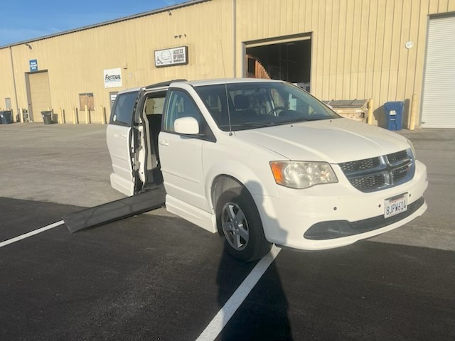 White wheelchair-accessible van with ramp extended in parking lot.