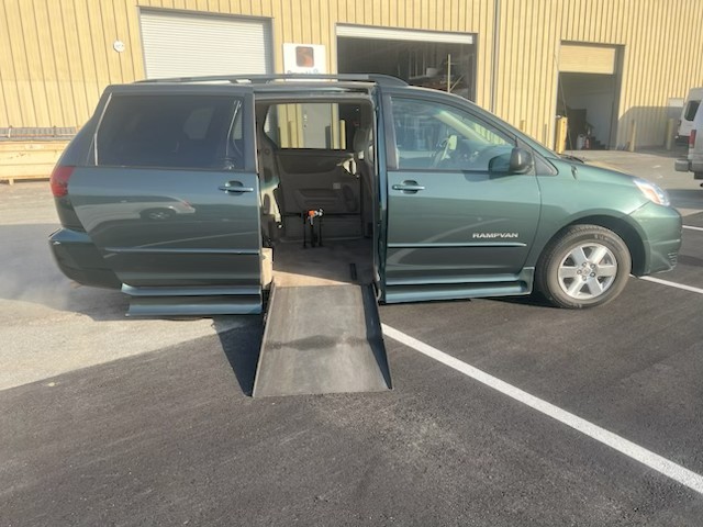 A wheelchair-accessible van with an extended ramp in a parking lot.