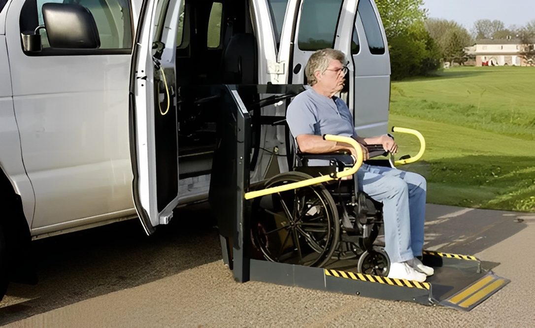 Man in wheelchair using a van's wheelchair lift outdoors.