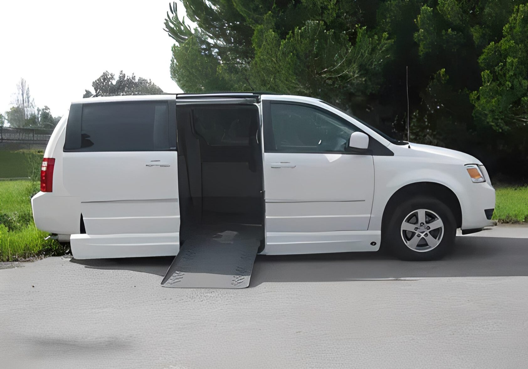 White wheelchair-accessible van with ramp extended on side.