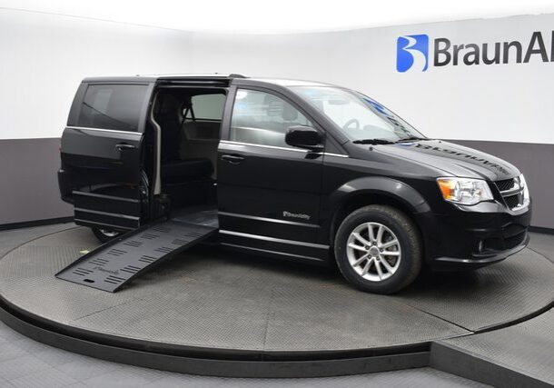 Black wheelchair-accessible van with side ramp deployed.