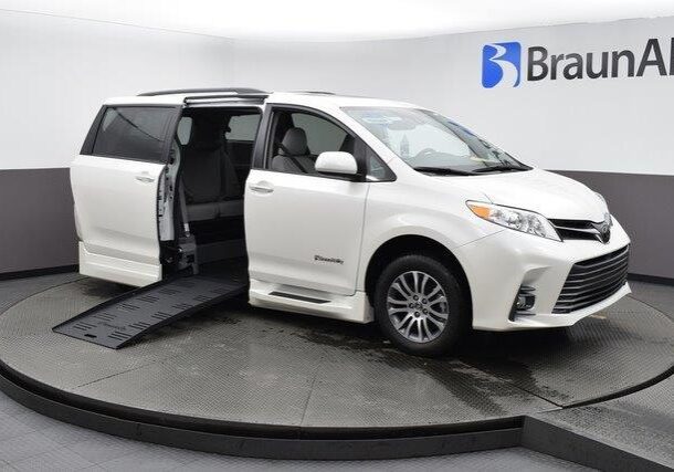 White wheelchair-accessible van with ramp extended on display.