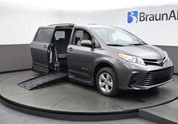 A gray wheelchair-accessible van with a lowered ramp deployed.
